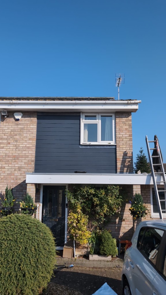 Dark grey cladding installation around an upper-floor window on a brick house