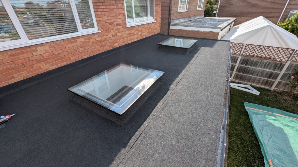 Completed dark grey flat roof with skylights after full replacement